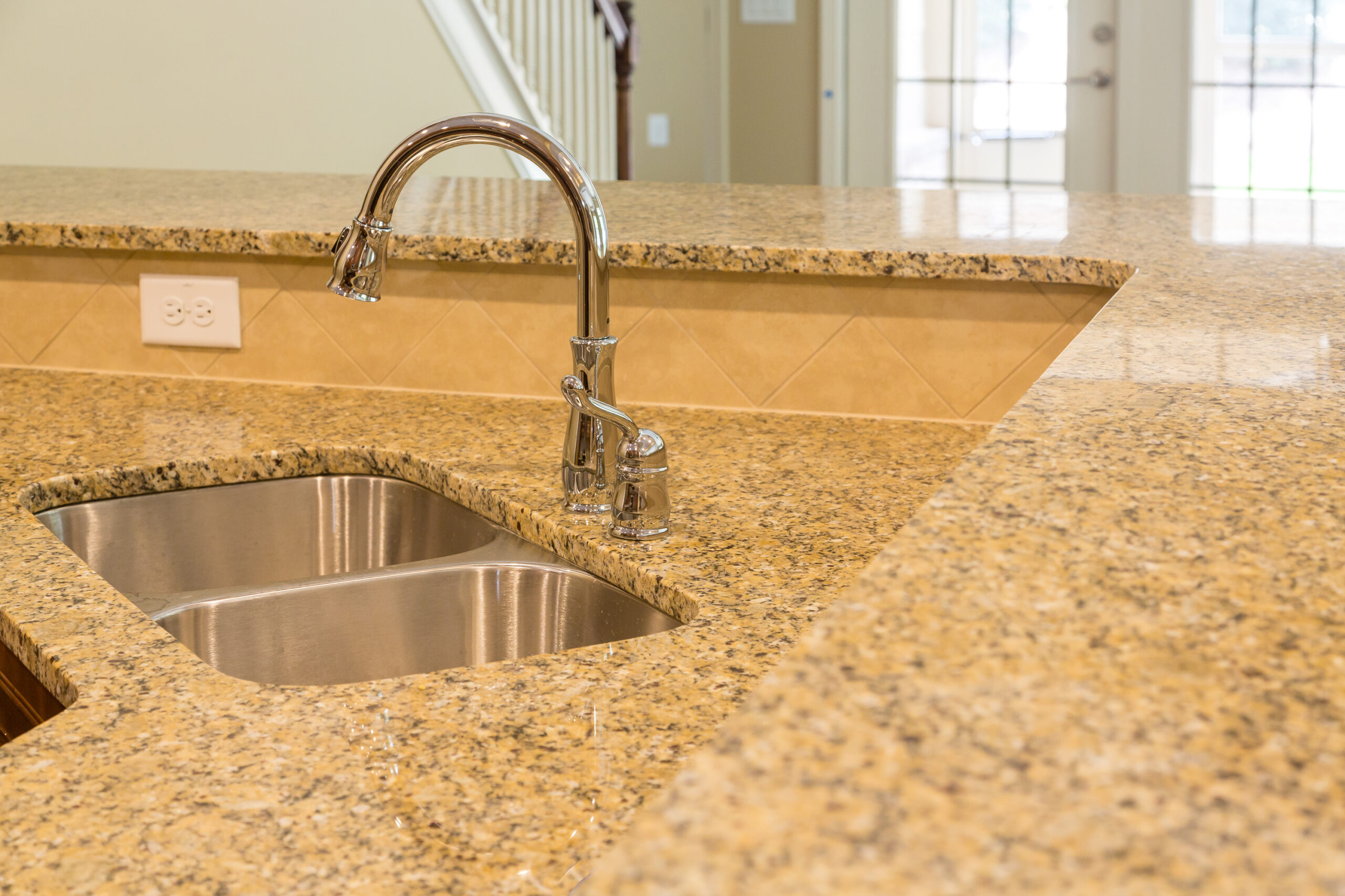 Stainless steel sink in tan granite countertop - Robins Plumbing Inc.