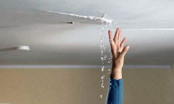 Crack in ceiling with water pouring out and hand reaching upwards towards crack for blog "Avoid Water Damage from Your Air Conditioner"