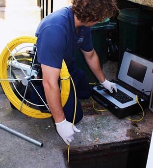 Plumbing tech using a sewer camera and monitor system for blog "Plumbing and Technology for Property Managers"