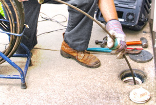 A plumber guiding a sewer camera into a pipe for an inspection for blog "Plumbing Inspection"