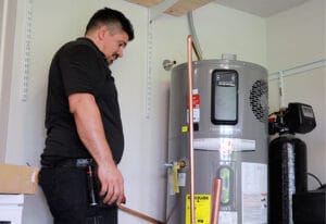 A plumbing technician at Robins Plumbing installing an electric hybrid water heater.